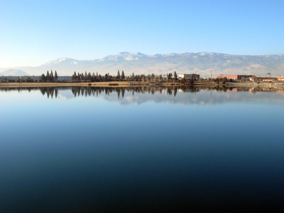 The Sierra's eastern front to the west of Reno is reflected in the Sparks Marina, where all of the fish have died over the past month _ an estimated total of 100,000 trout, bass and catfish _ on Friday, Jan. 17, 2014, in Sparks, Nev. Scientists say a sudden cold spurt in December likely caused a violent ``turnover'' of the 77-acre, man-made lake's waters that sucked out almost all the oxygen and killed the fish. (AP Photo/Scott Sonner).