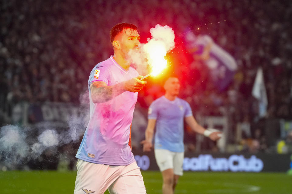 Lazio's Alessio Romagnoli holds a flare which was thrown onto the pitch during the quarterfinal Italian Cup soccer match between Lazio and Roma at Rome's Olympic Stadium, Wednesday, Jan. 10, 2024. (AP Photo/Gregorio Borgia)
