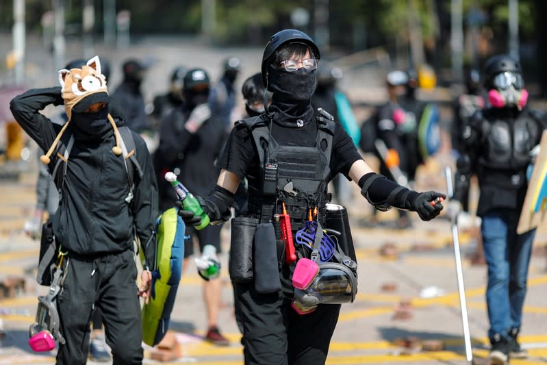 An anti-government protester holds a molotov cocktail alongside others on a road scattered with bricks outside the Polytechnic University in Hong Kong