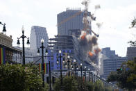 Two large cranes from the Hard Rock Hotel construction collapse come crashing down after being detonated for implosion in New Orleans, Sunday, Oct. 20, 2019. New Orleans officials set off several explosions Sunday intended to topple two cranes that had been looming precariously over the ruins of a partially collapsed hotel, but only one crane appeared to make it to the ground. (AP Photo/Gerald Herbert)