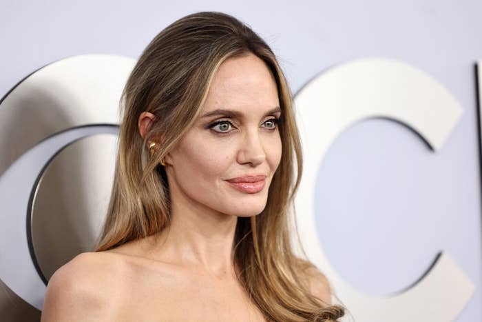 Angelina Jolie, wearing an off-shoulder gown, poses at an event for photographers