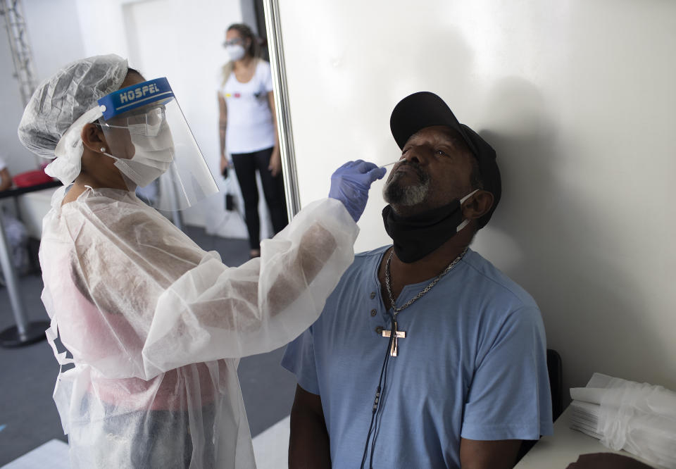 A health worker collects a nasal swab sample for a COVID-19 test in the Mare Complex favela of Rio de Janeiro, Brazil, Thursday, April 8, 2021. (AP Photo/Silvia Izquierdo)