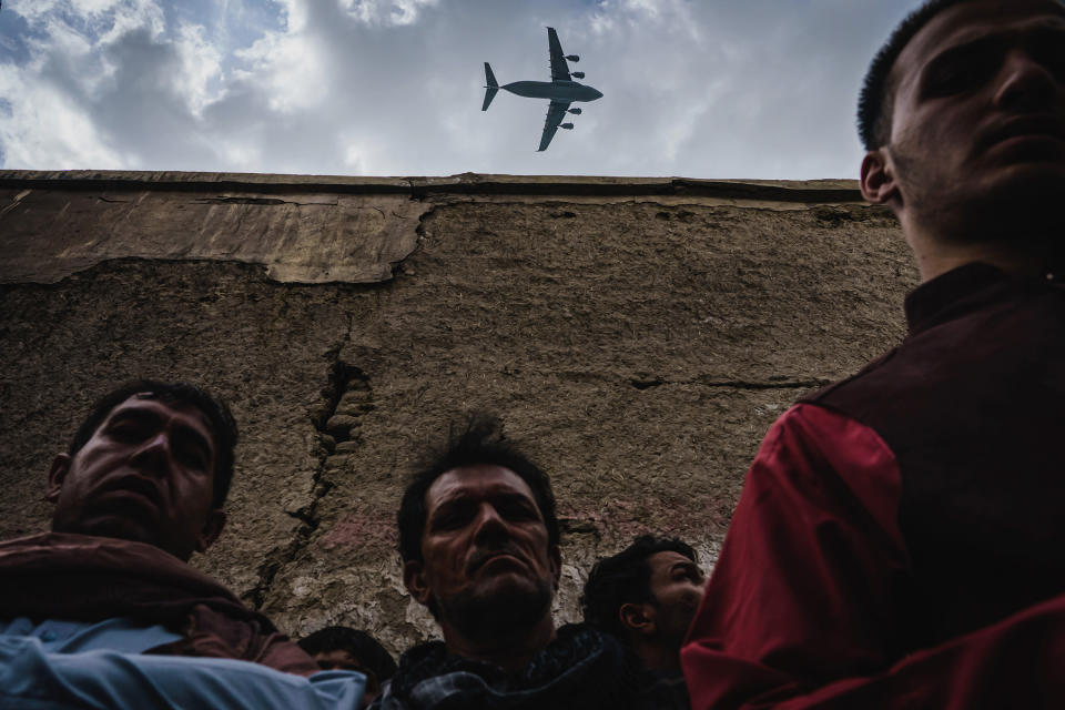 A military transport plane flies over relatives and neighbors of the Ahmadi family, who had gathered around the vehicle that was destroyed, on Aug. 30.<span class="copyright">Marcus Yam—Los Angeles Times/Getty Images</span>