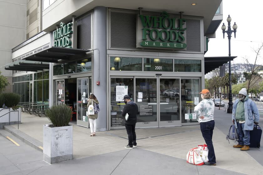 People maintain distance while waiting to enter a Whole Foods Market in San Francisco, Tuesday, March 31, 2020. (AP Photo/Jeff Chiu)