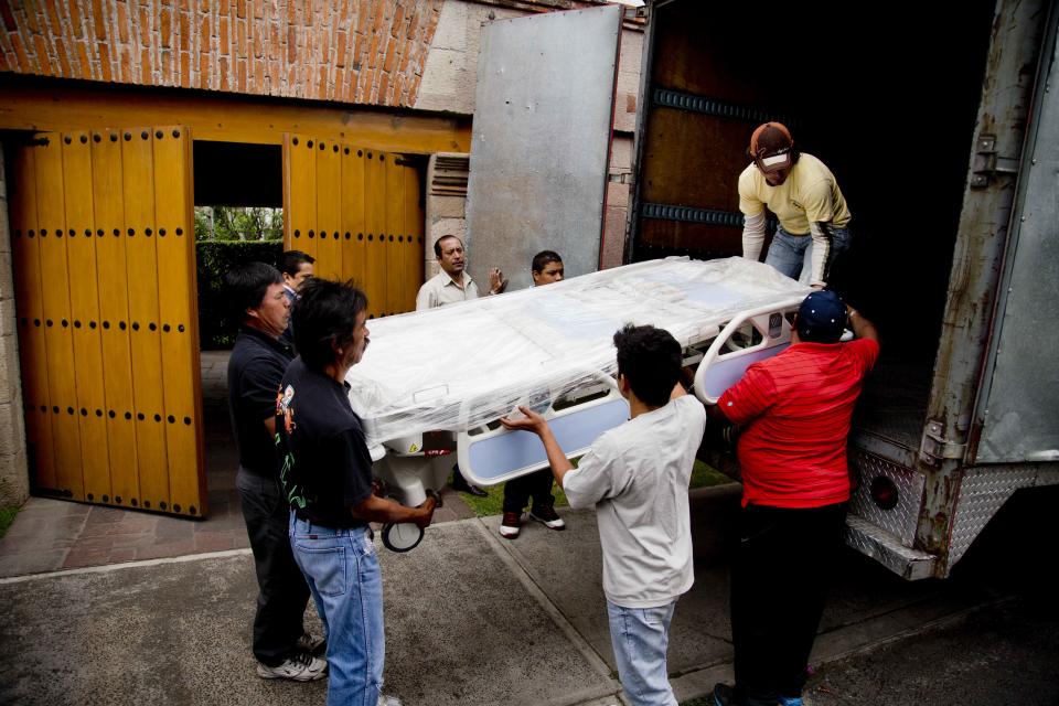A medical bed is lowered from a truck outside the home of Colombian author and Nobel literature laureate Gabriel Garcia Marquez in preparation for his return home from the hospital in Mexico City, Tuesday, April 8, 2014. A medical official says Garcia Marquez has left the hospital where he was treated for eight days for pneumonia and related problems. (AP Photo/Eduardo Verdugo)