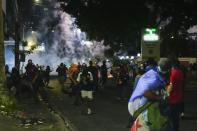 Manifestantes huyen del gas lacrimógeno lanzado en enfrentamientos con la policía en una protesta convocada contra un contrato aprobado recientemente entre el gobierno y la minera canadiense First Quantum, en Ciudad de Panamá, el miércoles 25 de octubre de 2023. (AP Foto/Arnulfo Franco)