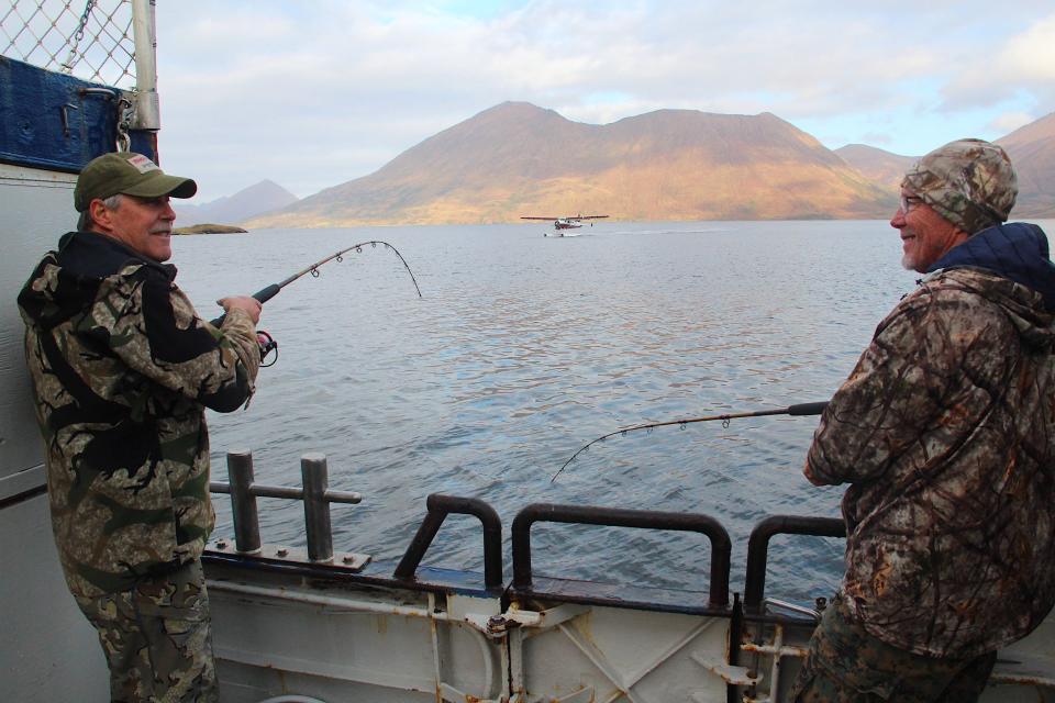 Jim Wipperfurth, left and Chuck Bongard, both of Sauk City, fish for cod while a float plane approaches along the coast of Kodiak Island, Alaska.