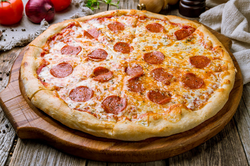 Pepperoni pizza on board on wooden background
