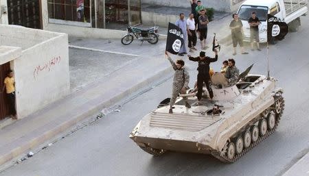 Militant Islamist fighters hold the flag of Islamic State (IS) while taking part in a military parade along the streets of northern Raqqa province in this June 30, 2014 file photo. REUTERS/Stringer/Files