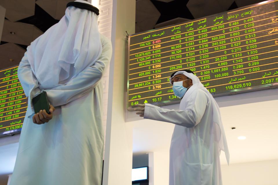 Jamal al-Khadhar, an executive vice president of the Dubai Financial Market, talks to a man on the floor of the exchange in Dubai, United Arab Emirates, Tuesday, July 7, 2020. Dubai reopened its Dubai Financial Market stock exchange Tuesday after closing its floor due to the coronavirus pandemic. (AP Photo/Jon Gambrell)