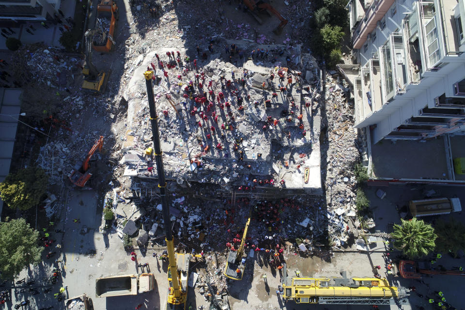 Photo taken with a drone shows rescue workers trying to save residents trapped in debris of a collapsed building, in Izmir, Turkey, Saturday, Oct. 31, 2020. Rescue teams on Saturday ploughed through concrete blocs and debris of eight collapsed buildings in search of survivors of a powerful earthquake that struck Turkey's Aegean coast and north of the Greek island of Samos, leaving unknown numbers of dead and injured. (IHA via AP)