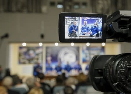Members of the International Space Station (ISS) crew (L to R) Jeff Williams of the U.S., Alexey Ovchinin and Oleg Skriprochka of Russia are seen on a camera screen during a news conference behind a glass wall at the Baikonur cosmodrome, Kazakhstan, March 17, 2016, ahead of their launch scheduled on March 19. REUTERS/Shamil Zhumatov