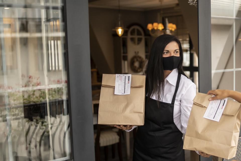 A server handing off a to-go order at a restaurant