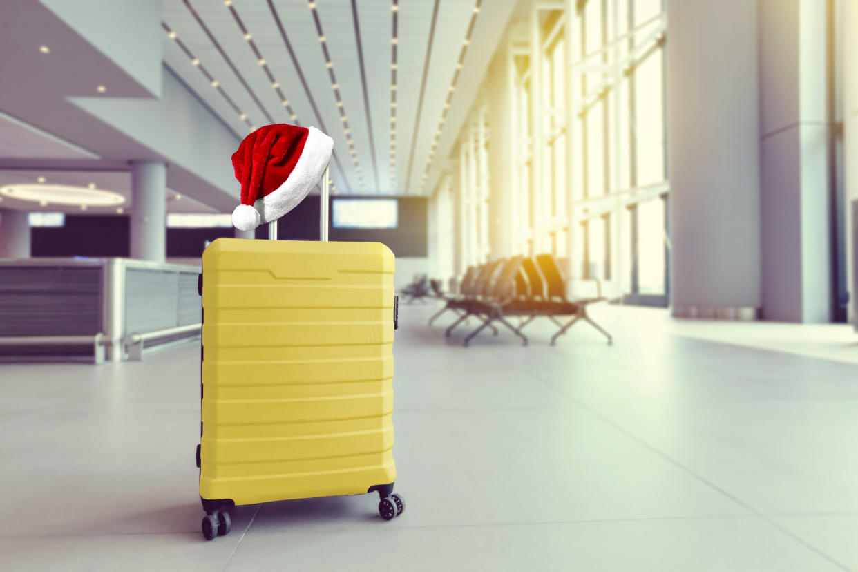 Santa hat on yellow suitcase in airport terminal, travel concept. New year holidays. Christmas vacation