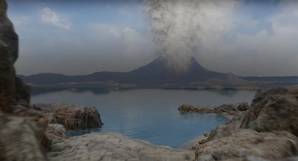 A volcano releasing smoke behind a lake