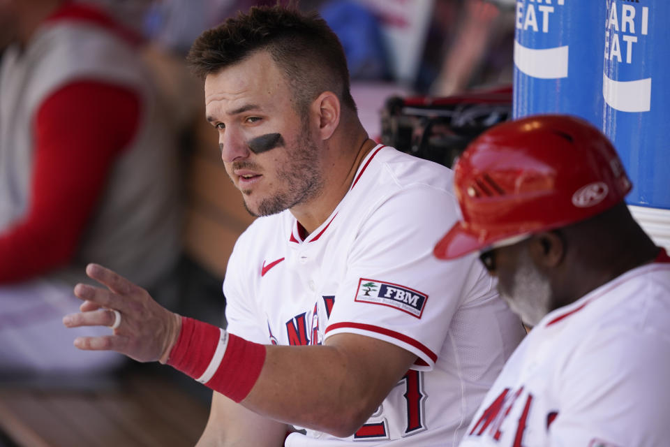 Los Angeles Angels designated hitter Mike Trout, left, speaks with third base coach Eric Young Sr. during the fifth inning of a baseball game against the Minnesota Twins, Sunday, April 28, 2024, in Anaheim, Calif. (AP Photo/Ryan Sun)