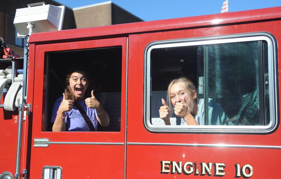 2022 Greater Alliance Carnation Festival 2nd Attendant Catarina Hagan, left, and 3rd Attendant Kenna McElroy give a thumbs-up as they ride Friday, Aug. 12, 2022, in a fire truck. Each court member had the chance to drive the truck in a closed parking lot.