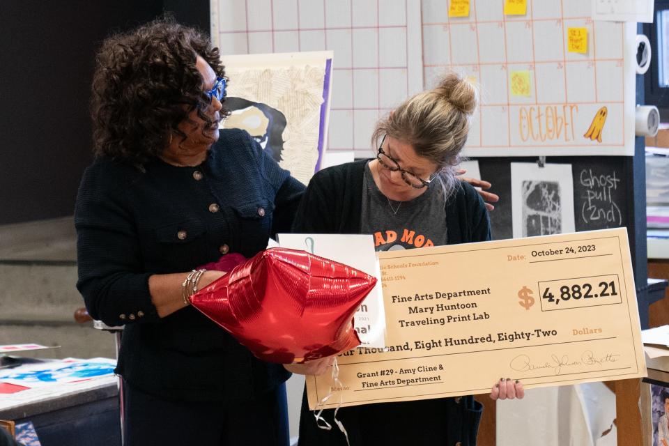Topeka Public Schools Foundation executive director Pamala Johnson-Betts presents a grant check for $4,882.21 to Topeka High art teacher Amy Cline for a traveling print lab Tuesday morning.