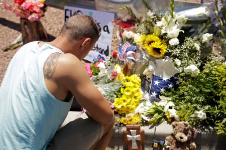 A man places flowers at the site the day after a mass shooting, at a Walmart in El Paso