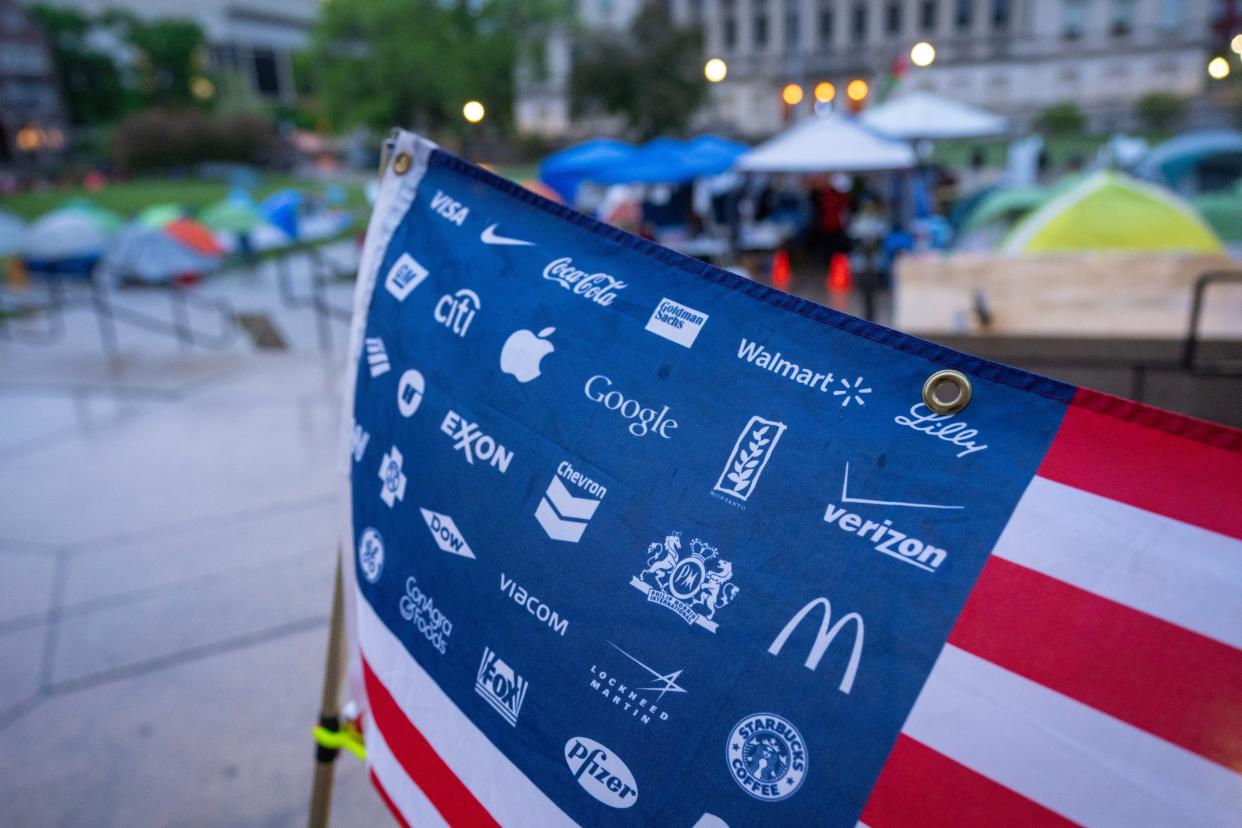 An American flag with the names and logos of large corporations substituted for stars is shown at an encampment protesting the Israel-Hamas war May 9 on Library Mall at the University of Wisconsin-Madison. Student protesters around the country have demanded colleges cut financial ties to Israel.