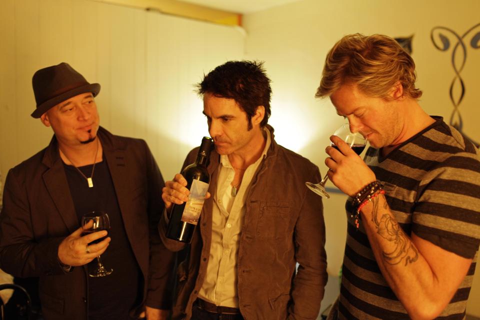 In this photo taken Wednesday April 11, 2012, from left, Jimmy Stafford, Patrick Monahan, and Scott Underwood of the band Train sample some of their wine before their concert at the Great American Music Hall in San Francisco. (AP Photo/Eric Risberg)