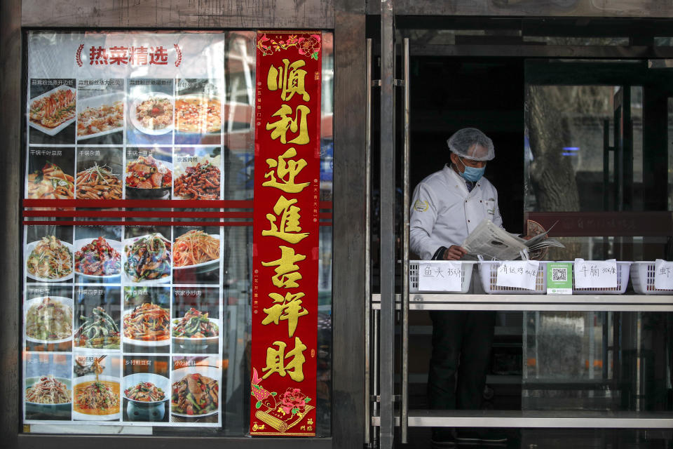 An employee wearing protective gear reads a newspaper at a restaurant only offering take-out orders following the coronavirus outbreak in Beijing, Sunday, March 1, 2020. Amid fears about where the next outbreak of a fast-spreading new virus would appear, infections and deaths continued to rise across the globe Sunday, emptying streets of tourists and workers, shaking economies and rewriting the realities of daily life. (AP Photo/Andy Wong)