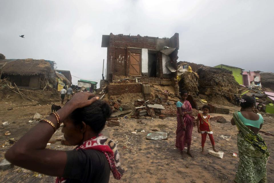 Fisherwomen and a girl stand in front of damaged house after Cyclone Phailin hit Puri