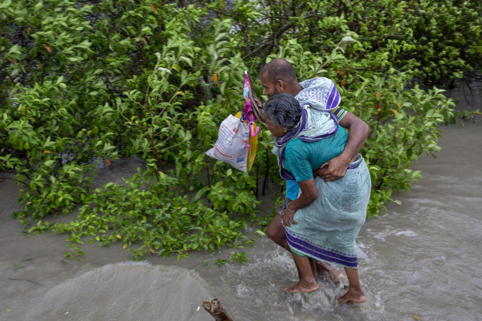 DAKOP, KHULNA, BANGLADESH - 2020/05/20: A man with his old mother walks through water after crosses the river by boat immediately before Cyclone Amphan hits Bangladesh costal area in Khulna. Authorities have scrambled to evacuate low lying areas in the path of Amphan, which is only the second "super cyclone" to form in the northeastern Indian Ocean since records began. (Photo by K M Asad/LightRocket via Getty Images)