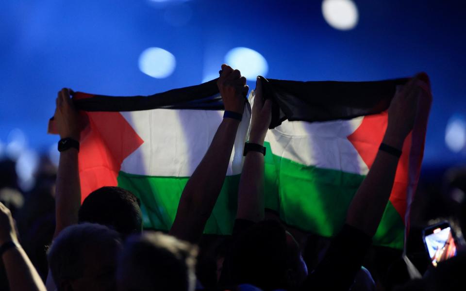 Members of the audience hold up Palestinian flags during the final dress rehearsal
