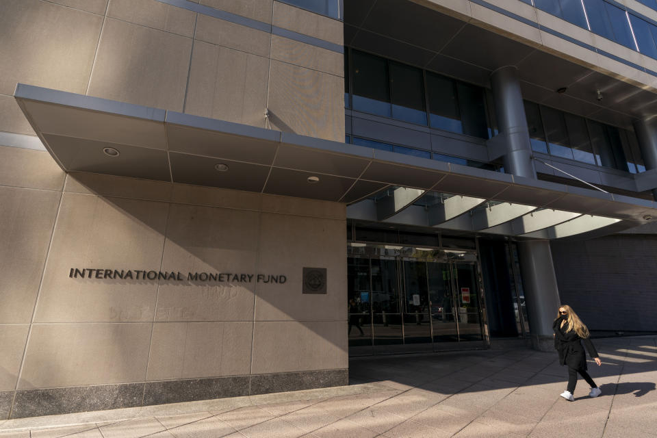 FILE - A pedestrian walks past the International Monetary Fund building, April 5, 2021, in Washington. The IMF is facing pressure to eliminate, or at least, reevaluate how it imposes fees on loans it disperses to needy countries like war-torn Ukraine — which is one of the fund's biggest borrowers. (AP Photo/Andrew Harnik, File)