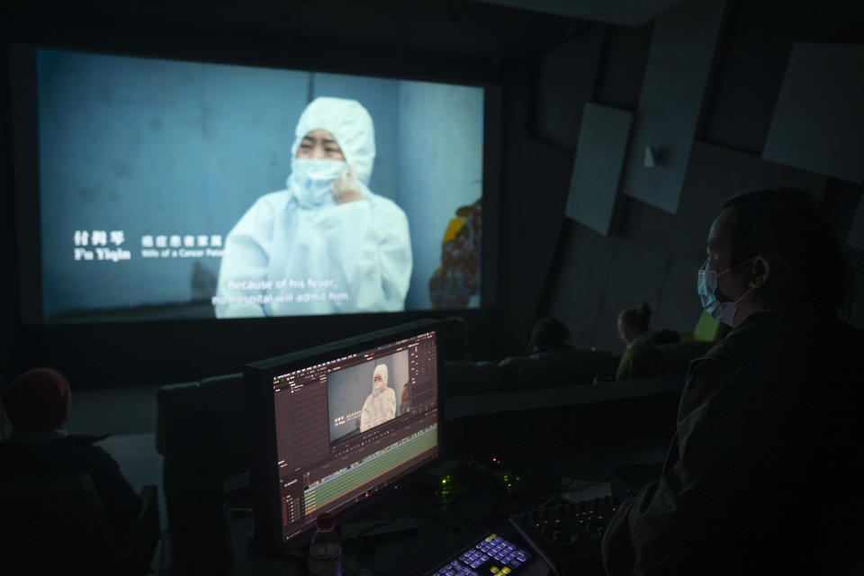 A production crew member watches as the documentary film "Wuhan, I Am Here" plays in a screening room in Beijing, Saturday, Jan. 15, 2022. The homeless, the sick, the elderly: For people who fell through the cracks of the official system, the then-unprecedented decision to isolate the central Chinese city of Wuhan and its 13 million people was a matter of life or death. Director Lan Bo hopes to sound the alarm with a documentary about volunteers who helped neighbors get food and medical care following the lockdown in early 2020 of the city where the coronavirus pandemic began. (AP Photo/Mark Schiefelbein)