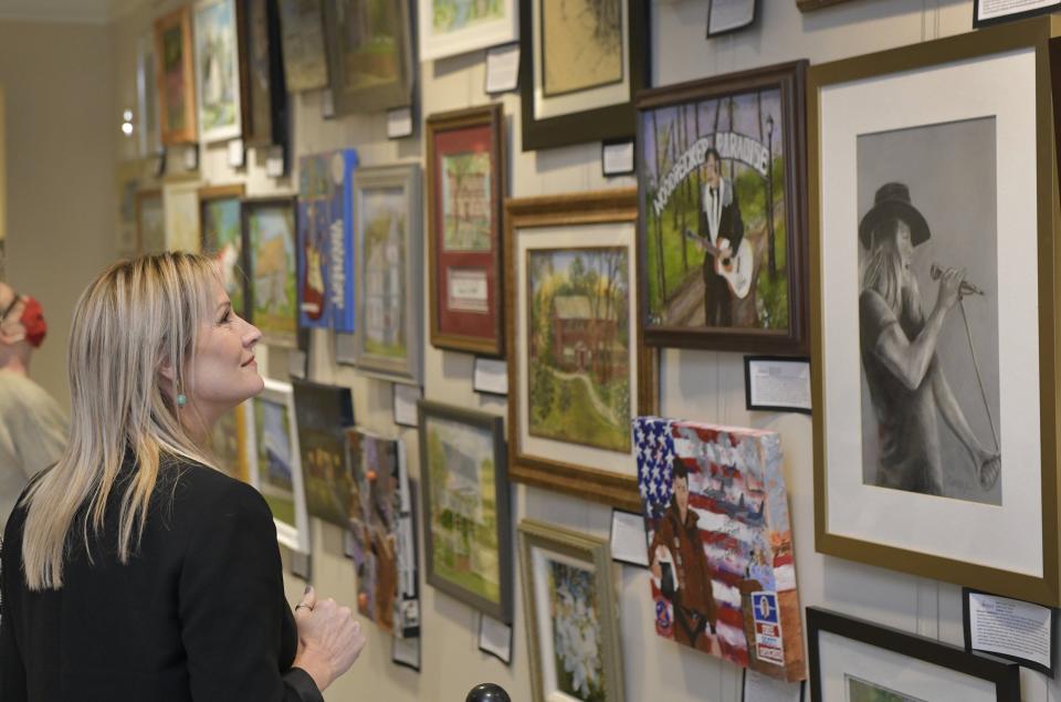 Tara Green, clerk of court and comptroller for Clay County, looks over the artwork on display at the new Clay County Art in the Courthouse gallery, including singers Slim Whitman and Donnie Van Zant from left to right.