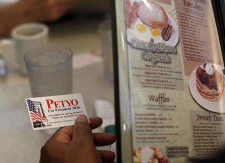 A customer at a restaurant holds a card given to him by U.S. Republican presidential candidate Michael Petyo in Portage, Indiana, United States, December 6, 2015. REUTERS/Jim Young