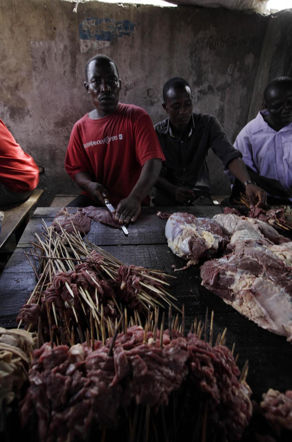 n this photo taken on Saturday, Oct. 20, 2012, men slice meat to prepare suya in Lagos, Nigeria. As night falls across Nigeria, men fan the flames of charcoal grills by candlelight or under naked light bulbs, the smoke rising in the air with the smell of spices and cooking meat. Despite the sometimes intense diversity of faith and ethnicity in this nation of 160 million people, that thinly sliced meat called suya, is eaten everywhere. (AP Photo/Sunday Alamba)