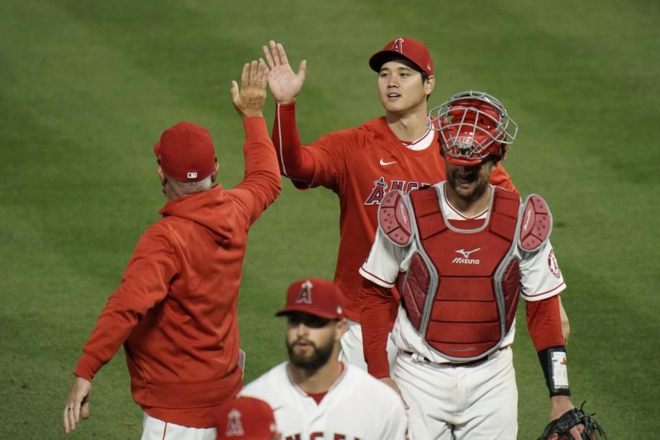 The Angels' Shohei Ohtani, top, gives manager Joe Maddon a high-five