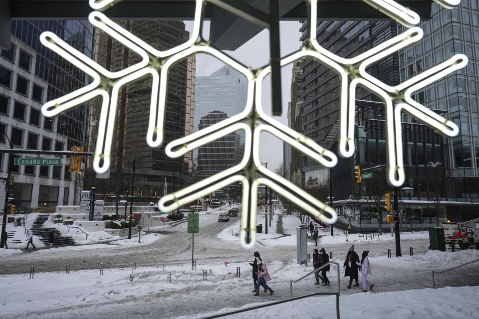 People walk in downtown Vancouver, British Columbia, Canada, as freezing rain falls, on Friday, Dec. 23, 2022. (Darryl Dyck/The Canadian Press via AP)