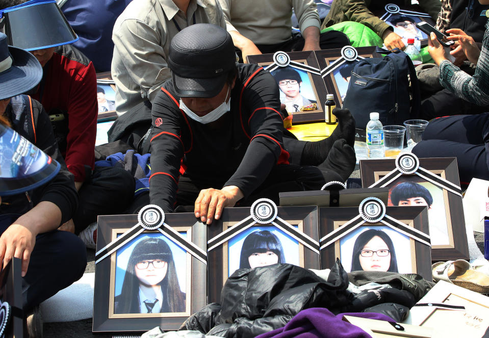 A family member of the victims of the sunken ferry Sewol displays portraits of victims near the presidential Blue House in Seoul, South Korea, Friday, May 9, 2014. Family members of the victims in the ferry sinking marched to the presidential Blue House in Seoul early Friday calling for a meeting with President Park Geun-hye but ended up sitting on streets near the presidential palace after police officers blocked them. Park's office said a senior presidential official plans to meet them later Friday. (AP Photo/Ahn Young-joon)