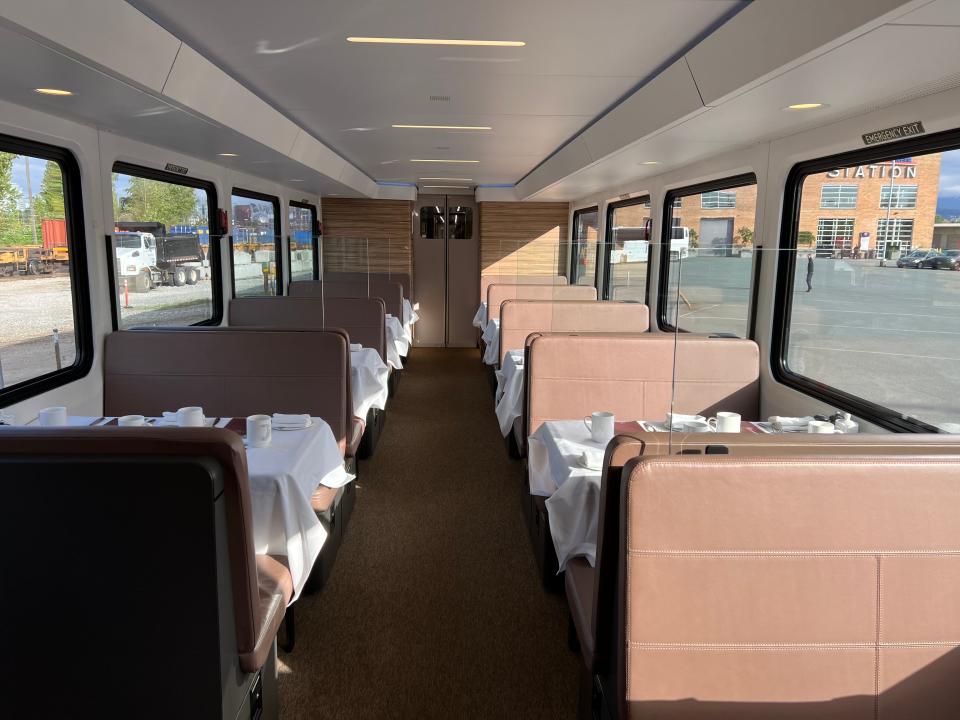 Dining car on train, with brown seats and tables covered with white tablecloths