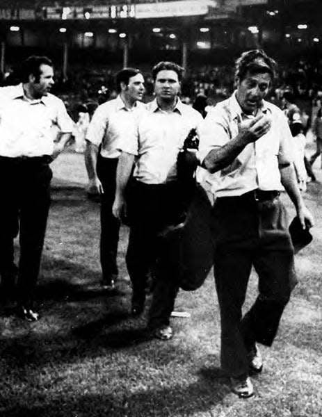 Nestor Chylak, far right, checks a scalp wound as he leads umpires off the field after the 10-cent beer night riot on June 4, 1974, at Cleveland Stadium. The umpires for the Cleveland-Texas game were, left to right, Joe Brinkman, Nick Bremigan, Larry McCoy, and Chylak.