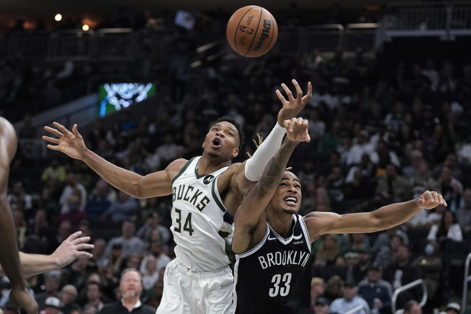 Milwaukee Bucks' Giannis Antetokounmpo (34) and Brooklyn Nets' Nicolas Claxton (33) reach for the ball during the first half of an NBA basketball game Tuesday, Oct. 19, 2021, in Milwaukee. (AP Photo/Morry Gash)