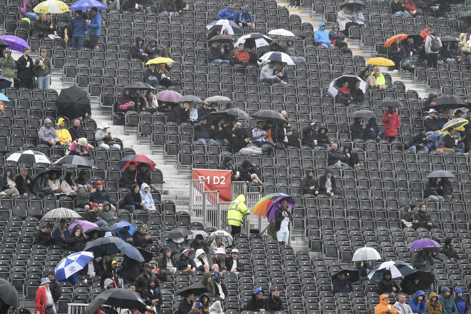 Fans cover from the rain as they wait for the start of the fifth day of the fourth Ashes Test match between England and Australia at Old Trafford, Manchester, England, Sunday, July 23, 2023. (AP Photo/Rui Vieira)