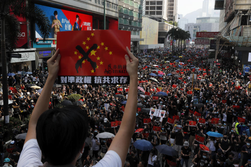 A protester holds up a placard reading "Aligning the regime, Anti Communist survival" as demonstrators march in Hong Kong, Sunday, Oct. 20, 2019. Hong Kong protesters again flooded streets on Sunday, ignoring a police ban on the rally and demanding the government meet their demands for accountability and political rights. (AP Photo/Kin Cheung)