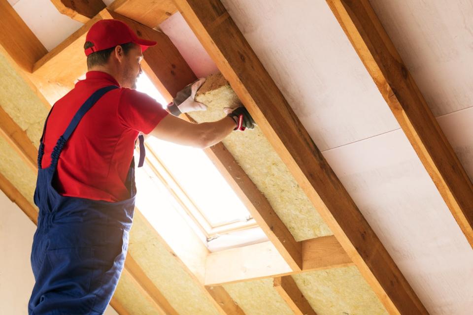 house attic insulation - construction worker installing rock wool in mansard wall