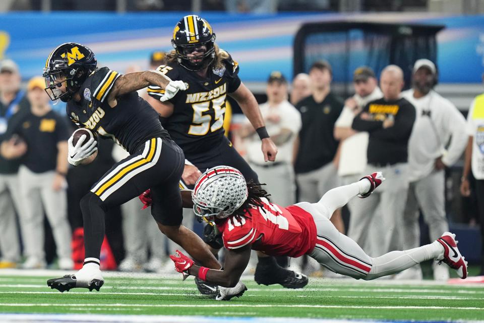 Dec 29, 2023; Arlington, Texas, USA; Ohio State Buckeyes cornerback Denzel Burke (10) tackles Missouri Tigers wide receiver Theo Wease Jr. (1) during the second quarter of the Goodyear Cotton Bowl Classic at AT&T Stadium.