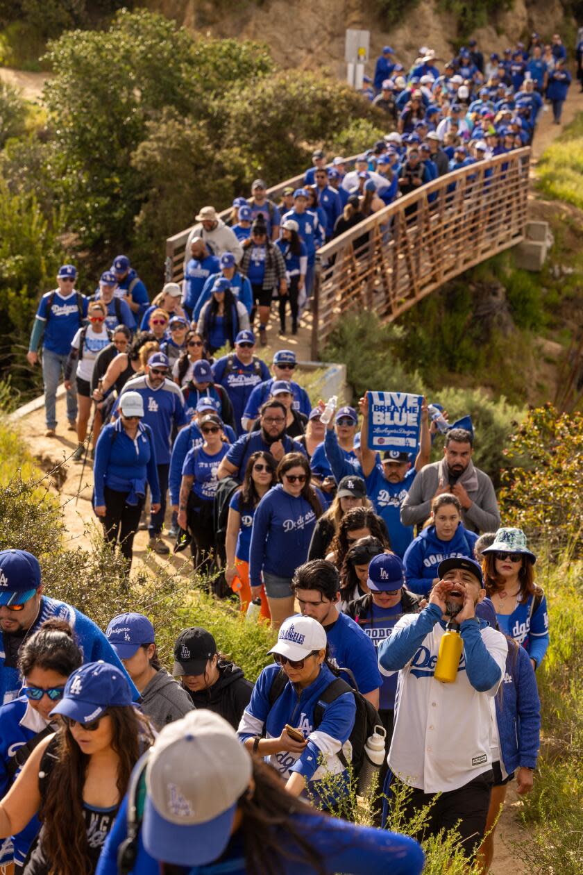 Throngs of hikers including the Dodgers Blue Hiking Crew make their way across a bridge.