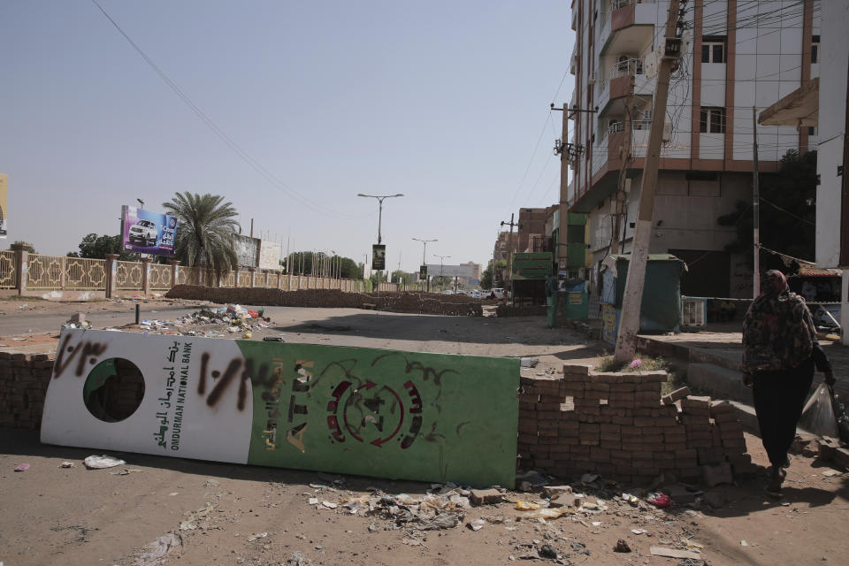 People walk past a barricade in Khartoum, Sudan, Sunday, Nov. 7, 2021. Sudan's protest movement has rejected internationally backed initiatives to return to a power-sharing arrangement with the military after last month's coup, (AP Photo/Marwan Ali)