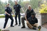 Kevin Burton-Crow, upper-right, of the Thurston Co. Sheriff's Dept., handcuffs Naseem Coaxum, right, an actor playing the role of a person causing a disturbance at a convenience store, during a training class at the Washington state Criminal Justice Training Commission, Wednesday, July 14, 2021, in Burien, Wash., instructor Ken Westphal, second from left, an officer with the Lacey Police Dept., and LeAnne Cone, left, of the Vancouver Police Dept., look on. Washington state is embarking on a massive experiment in police reform and accountability following the racial justice protests that erupted after George Floyd's murder last year, with nearly a dozen new laws that took effect Sunday, July 25 but law enforcement officials remain uncertain about what they require in how officers might respond — or not respond — to certain situations, including active crime scenes and mental health crises. (AP Photo/Ted S. Warren)