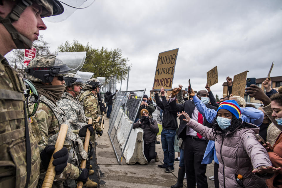 CORRECTS TO IDENTIFY PEOPLE AT LEFT AS GUARDSMEN NOT POLICE - Protesters confront National Guardsmen, Monday, April 12, 2021, at the Brooklyn Center Police Department in Brooklyn Center, Minn., as they protest the fatal police shooting of Daunte Wright. (Richard Tsong-Taatarii/Star Tribune via AP)