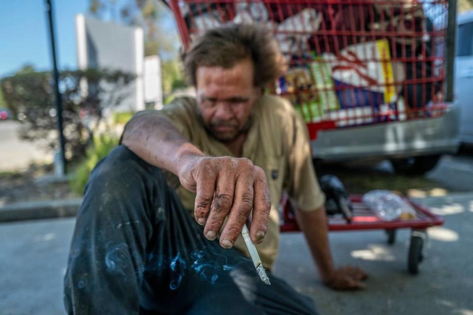 Mark Rippee, 59, who is blind, rests on the ground holding a cigarette in Vacaville on July 27, 2022. Renée C. Byer/rbyer@sacbee.com