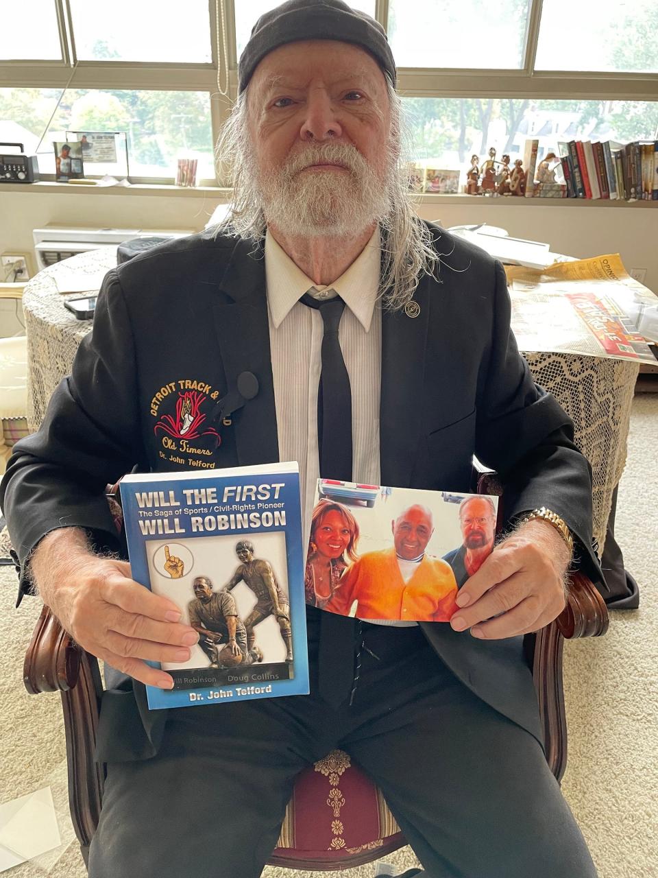 From his home at the River House Co-Op on Oct. 12, Dr. John Telford was proud to display how he has remained connected to Will Robinson, who he worked closely with at Pershing High School during a time when Robinson also was a scout for the Detroit Lions. The book Telford is holding is a tribute to Robinson written by Telford. Pictured on the book's cover is a statue of Robinson and a young Doug Collins, who Robinson nurtured at Illinois State before Collins' NBA career, which included coaching the Detroit Pistons.